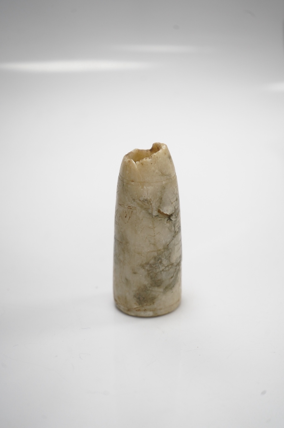 An Egyptian incised alabaster cosmetics bottle (bullet shaped), 7.5cm. Condition - restored